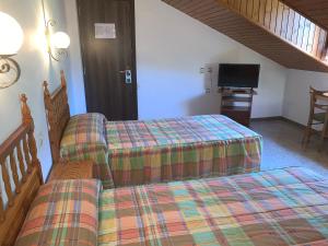 two twin beds in a room with a tv at Alberg Vall de Boi in Barruera