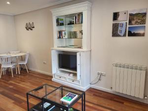 a living room with a tv in a white cabinet at Apartamento BRUMA DE LUARCA in Luarca