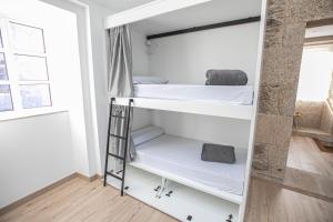 um quarto com 2 beliches e uma escada em Albergue A Fabrica em Santiago de Compostela