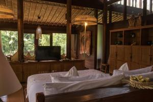a bedroom with a bed and a desk and windows at Dua Dari, a Residence by Hadiprana in Ubud