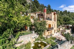 une vieille maison avec un étang en face de celle-ci dans l'établissement Ifigenia Theriso Village, à Thérison