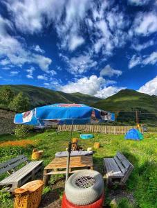 a picnic table with a blue umbrella and a bench at Warm House in Stepantsminda