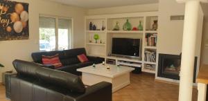 een woonkamer met een zwarte leren bank en een tv bij La provençale in Roquevaire