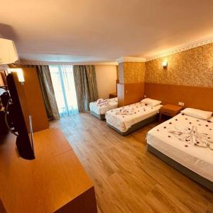 a hotel room with two beds and a television at Britannia Hotel Village in Kemer