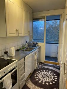 uma cozinha com armários brancos, um lavatório e uma janela em Lovely Apartment em Gotemburgo