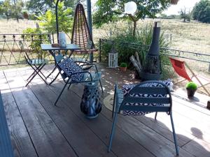 a deck with chairs and a table and a stove at La roulotte d'Elicie Proche du Parc le Pal in Saint-Agnan-sur-Loire