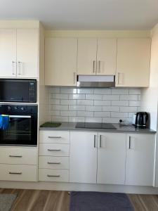 una cocina con armarios blancos y un aparato negro en Royal Lodge - A Luxury Lifestyle en Melbourne