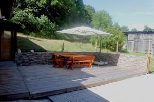 une terrasse en bois avec une table et un parasol dans l'établissement Hof Sonnegg - Naturpark Jauerling - Wachau, à Maria Laach am Jauerling