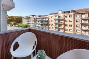 2 weiße Stühle auf einem Balkon mit einem Gebäude in der Unterkunft Liberdade Home Stay - Minho's Guest in Braga