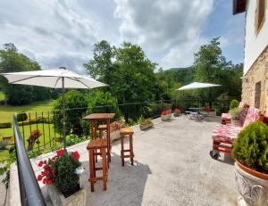 un patio avec une table, des chaises et un parasol dans l'établissement Vivienda Rural - Apartamentos La Cueva - Hornedo, à Entrambasaguas