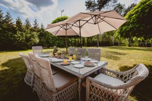an outdoor table with an umbrella and chairs at Golden Glamping nad Narwią in Lubiel Stary