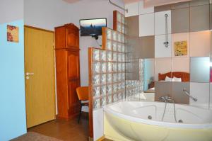 ブラショヴにあるPension Flamingoのバスルーム(バスタブ付)、壁掛けテレビが備わります。