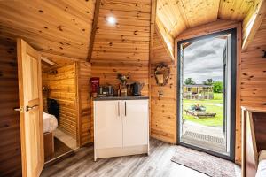 a kitchen in a log cabin with a large window at Delny Glamping and Farm Animals in Invergordon