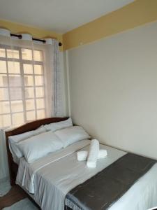 1 dormitorio con 1 cama con sábanas blancas y ventana en Grey Homes, 2 bedroom apartments along mombasa road, near JKIA & SGR Nairobi, en Syokimau