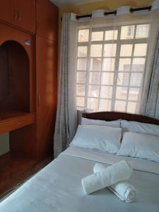 1 cama con 2 toallas y ventana en Grey Homes, 2 bedroom apartments along mombasa road, near JKIA & SGR Nairobi, en Syokimau