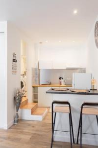 een keuken met witte kasten en een aanrecht met krukken bij Magnifique studio à Bompard proche de la plage in Marseille