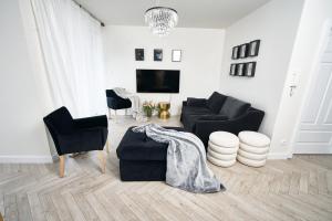 uma sala de estar com um sofá e cadeiras e uma televisão em SZAFIROWE APARTAMENTY 3 kryty basen i sauna RESORT KLIFOWA em Rewal