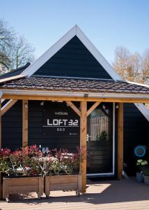 Loft 32 في Winsum: مبنى اسود وامامه زهور