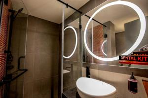 a bathroom with a toilet and a round mirror at Ginger Surat in Surat