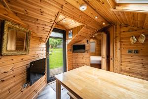 Cabaña de madera con mesa de madera en una habitación en Delny Glamping and Farm Animals en Invergordon