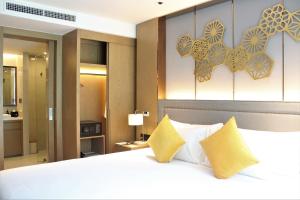 a bedroom with a large white bed with yellow pillows at Wyndham La Vita Rawai Phuket in Rawai Beach