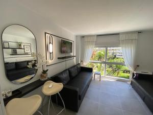 a living room with a black couch and a mirror at Modern Sea view Studio In Benal Beach in Benalmádena