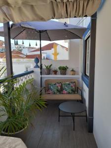 a porch with a bench and an umbrella at Cantinho do Céu in Alcácer do Sal