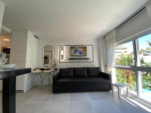 a living room with a black couch and a kitchen at Modern Sea view Studio In Benal Beach in Benalmádena