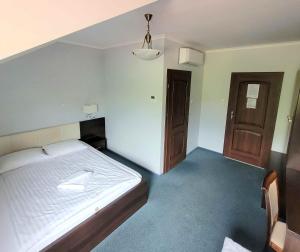 a bedroom with a white bed and two wooden doors at Chelosiowy Dworek in Jaworznia