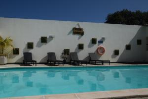 a white wall with chairs and a swimming pool at Casa vereda Two, Ponta Delgada, S Miguel in Ponta Delgada