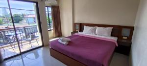 a bedroom with a bed with a purple blanket and a balcony at KANPAI HOTEL in Patong Beach