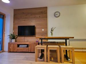 a living room with a table and a tv on a wall at Apartment Iris in Bohinj