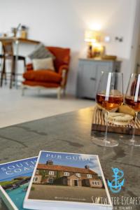 a table with two glasses of wine and a magazine at Our Lookout at Grand Banks in Teignmouth