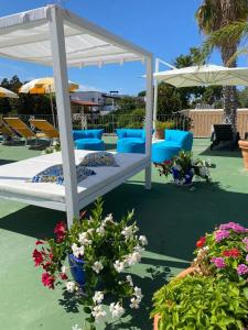 un letto su un patio con fiori e ombrelloni di Hotel Parco Delle Agavi a Ischia