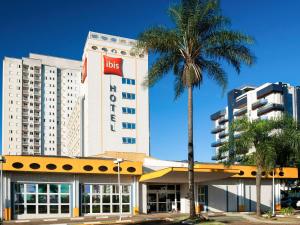 a hotel with a palm tree in front of a building at Ibis São Carlos in São Carlos