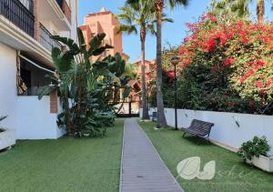 a walkway in a yard with a bench and flowers at PUSHE Playa Granada Beach & Golf 17 in Motril