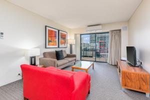 a living room with a red couch and a tv at Mantra on Hay Perth in Perth
