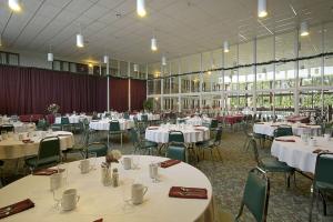 un salón de banquetes con mesas y sillas blancas en Howard Johnson by Wyndham Portage La Prairie, en Portage La Prairie