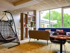 Cette chambre comprend un canapé, une chaise et une table. dans l'établissement Novotel Paris Créteil Le Lac, à Créteil