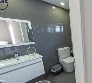 ein Badezimmer mit einem WC, einem Waschbecken und einem Spiegel in der Unterkunft WE ARE HOSTEL in Póvoa de Varzim