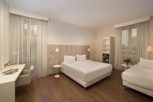 a hotel room with two beds and a desk at NH Genova Centro in Genoa