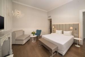 a bedroom with a large white bed and a couch at NH Genova Centro in Genoa