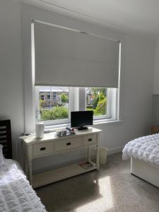 a bedroom with a desk with a monitor and a window at Giffnock Rooms in Giffnock