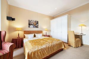 a bedroom with a bed and two tables and a chair at Strandhotel Sylt Westerland in Westerland