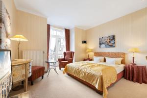 a hotel room with a bed and a chair at Strandhotel Sylt Westerland in Westerland