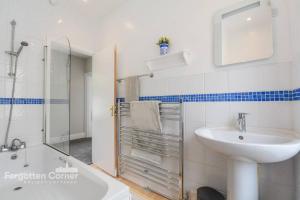 a white bathroom with a sink and a shower at Woodleigh in Cawsand