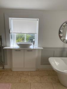 a white bathroom with a sink and a window at Giffnock Rooms in Giffnock