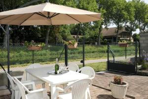einen weißen Tisch und Stühle mit Sonnenschirm in der Unterkunft Le claujovin in Méry-sur-Seine