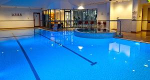 - une grande piscine d'eau bleue dans un bâtiment dans l'établissement DoubleTree by Hilton Coventry, à Coventry