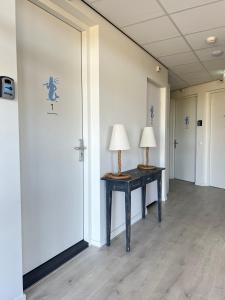 un couloir vide avec deux lampes sur une table dans l'établissement Neptunus Appartementen, à Bergen aan Zee